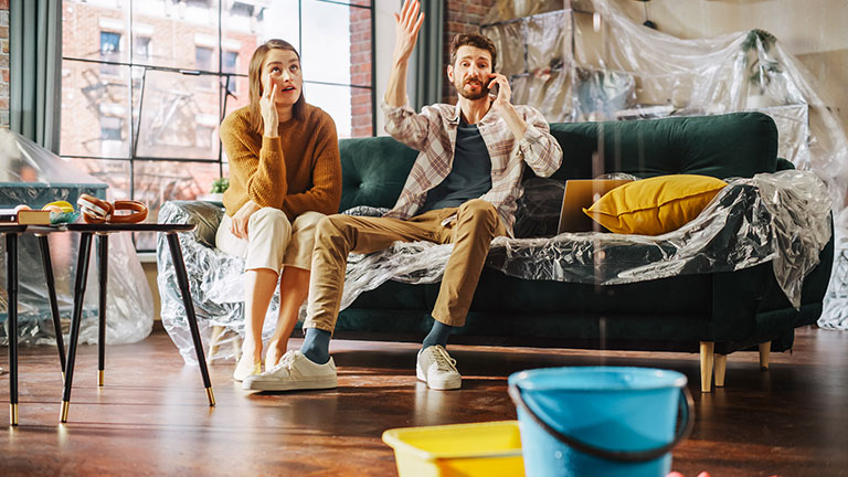 Roof is Leaking, Pipe Rupture at Home: Angry Couple Calling Insurance Company, Screaming into Phone in Frustration, Trying to Find Plumber, Master. Water Drips into Buckets in Living Room. Rack Focus Credit:gorodenkoff