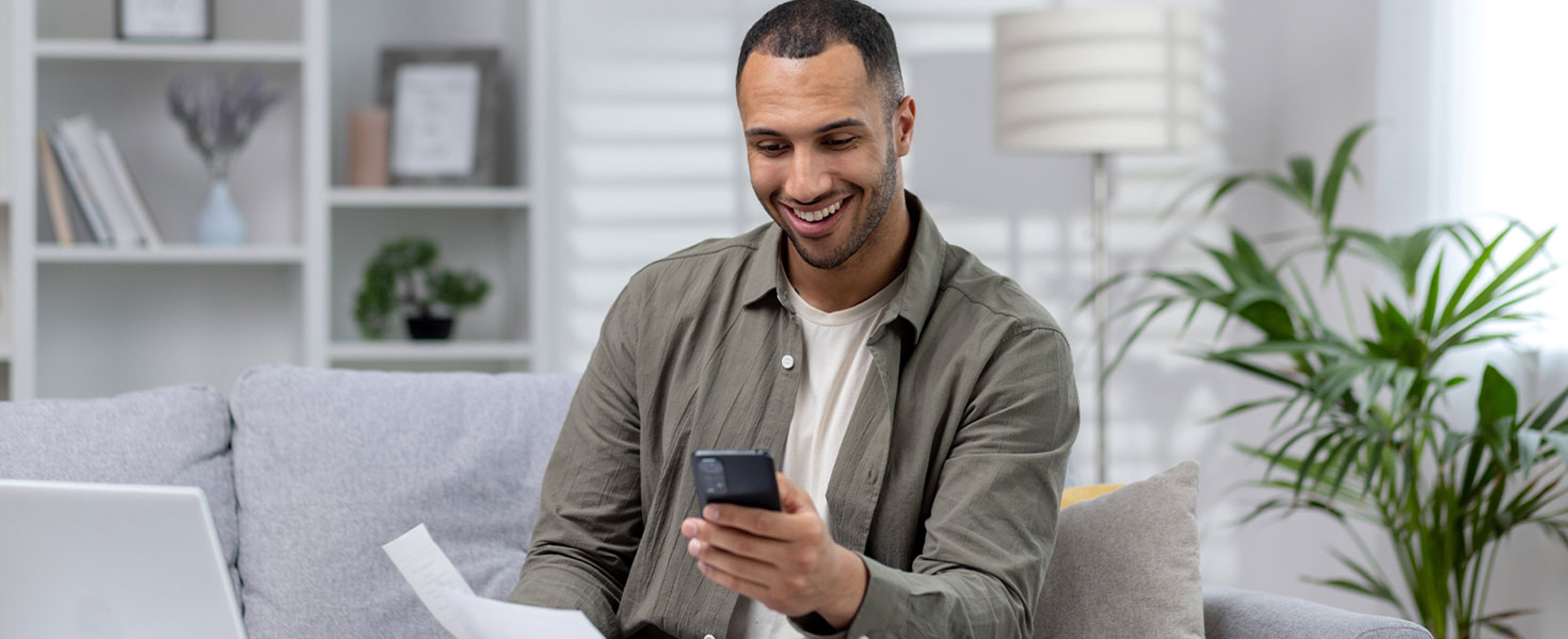 man looking at phone holding paper