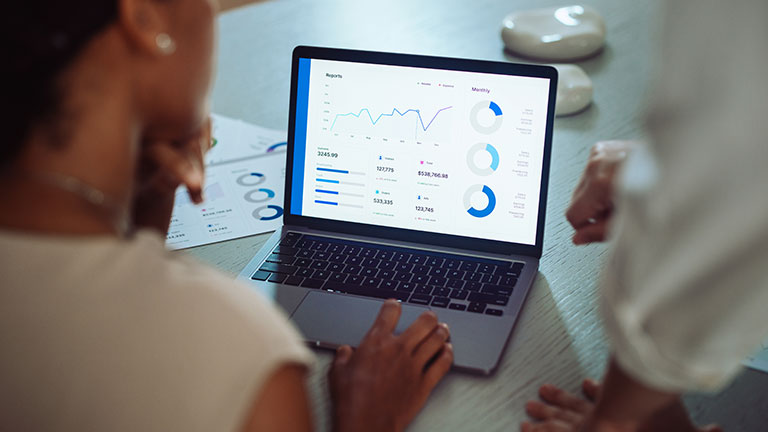 Businesswomen Analyzing Sales Data on Laptop in Office