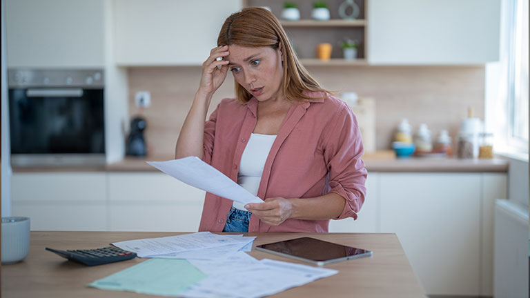 Stressed young woman having financial problems at home calculating domestic bills