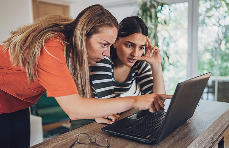 Two young woman experiencing online fraud and trying to solve it