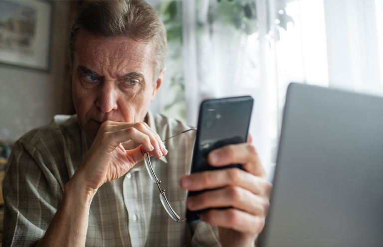 Senior man looking seriously at smartphone