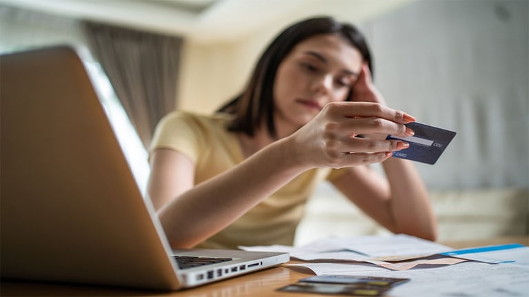 woman holding credit card in front of laptop 