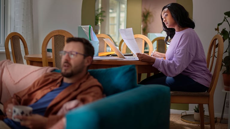 woman sitting with laptop, man sitting on couch 