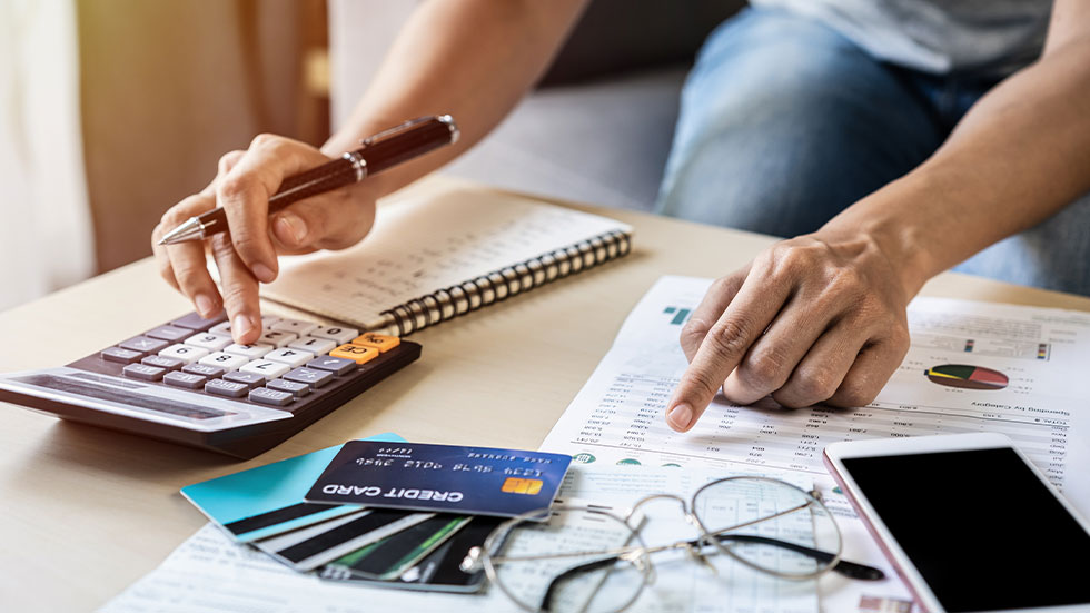 Person with credit cards, documents, calculator on table