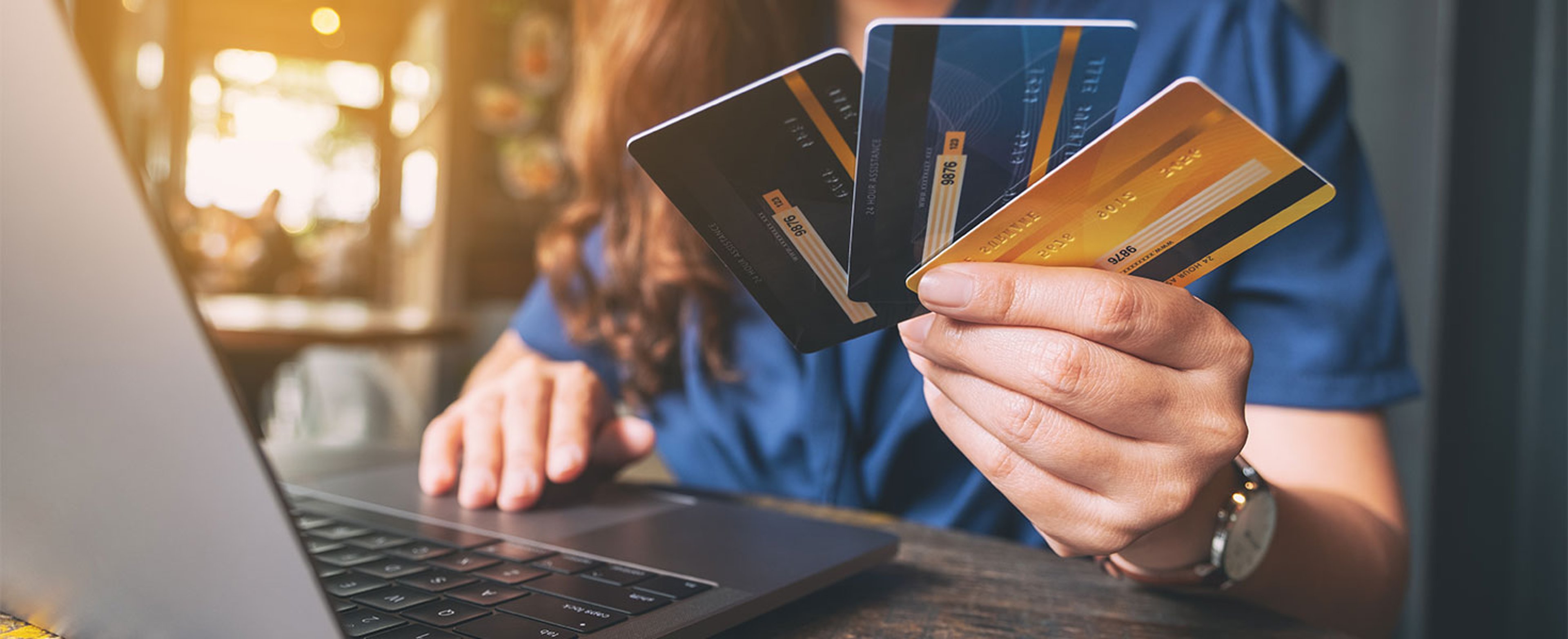 woman using laptop holding three credit cards