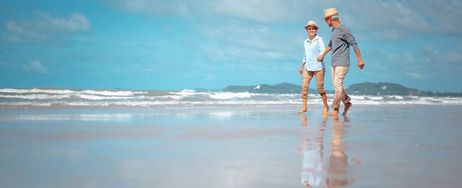 elderly couple walking on beach