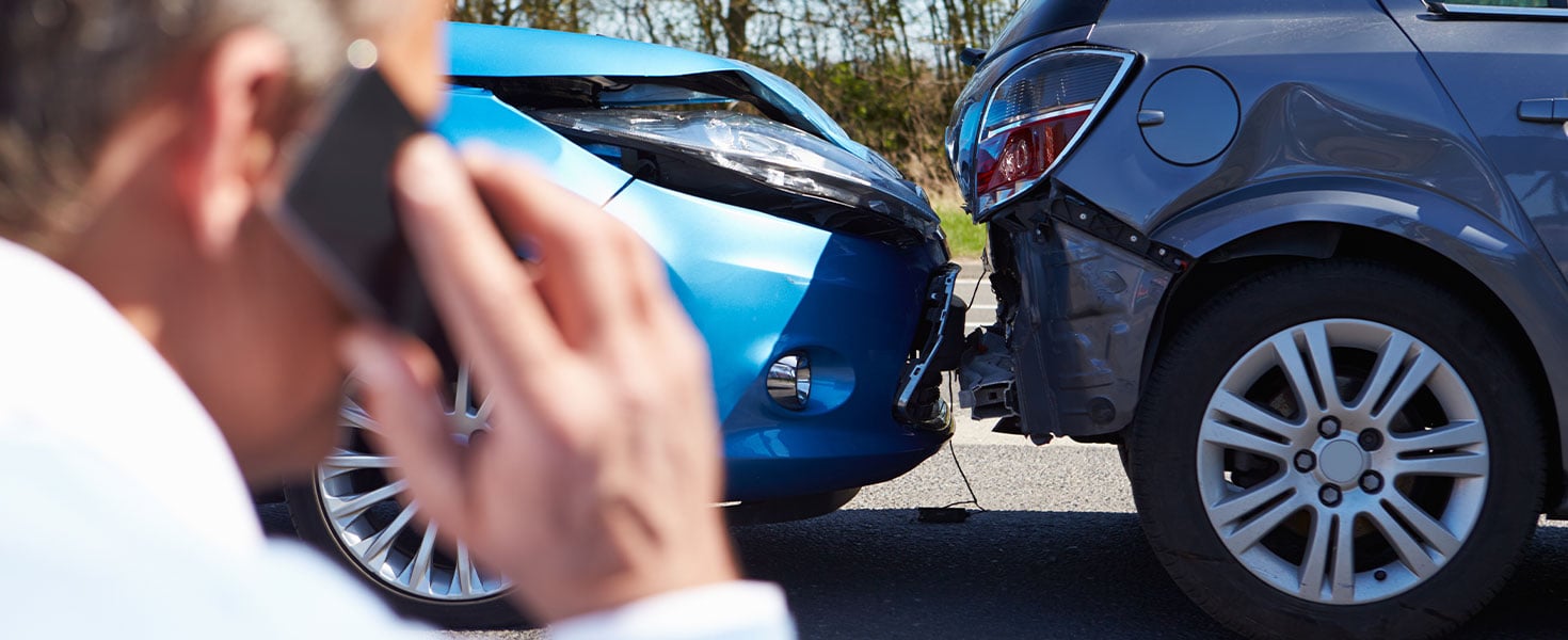 man making phone call, car accident in background
