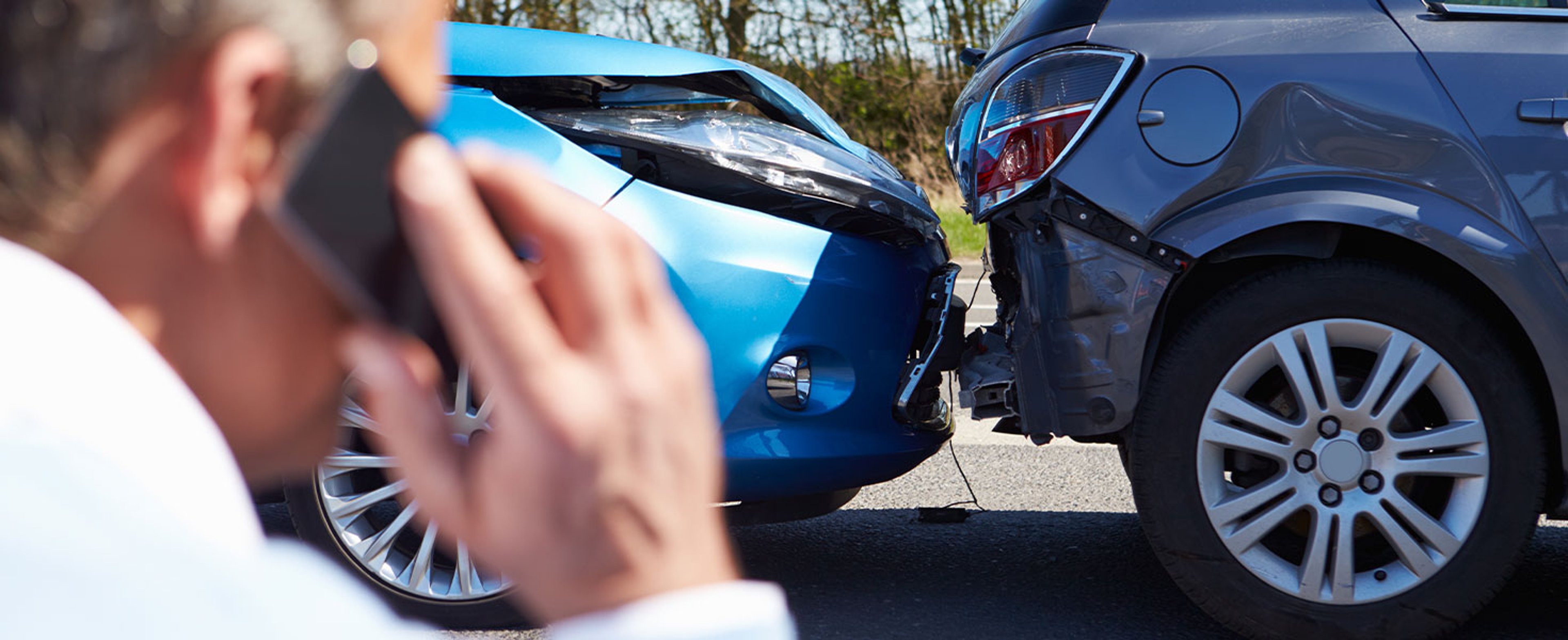 man making phone call, car accident in background