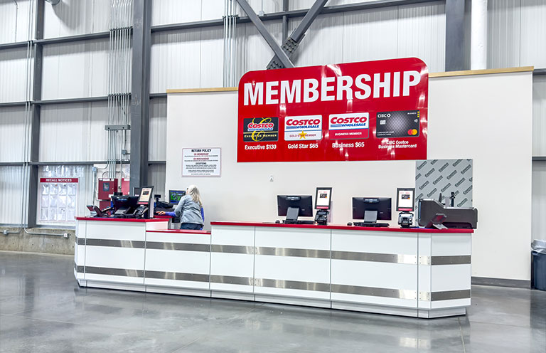 costco membership counter with posters of membership tiers on wall behind counter