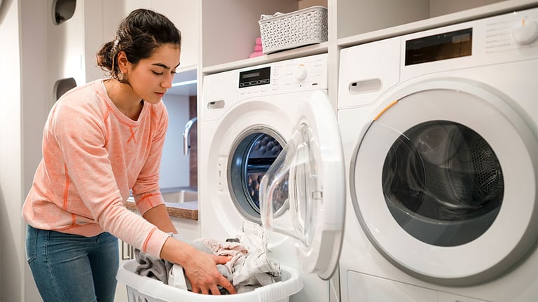Woman doing her laundry while at home in the Northeast of England. She is taking out the clothes and putting them into a laundry basket. Credit:SolStock