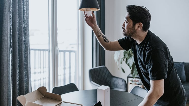 Japanese man installing smart lightbulb and connecting it with mobile app. Credit:visualspace