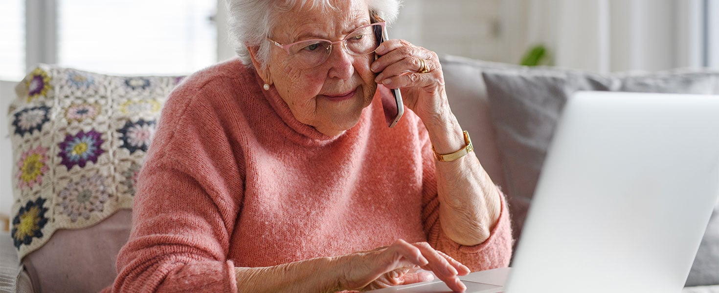 elder woman using phone and laptop