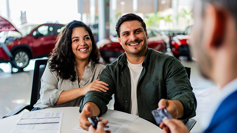 Couple signing receiving car key at car