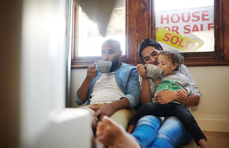 family sitting inside home that has sold signs