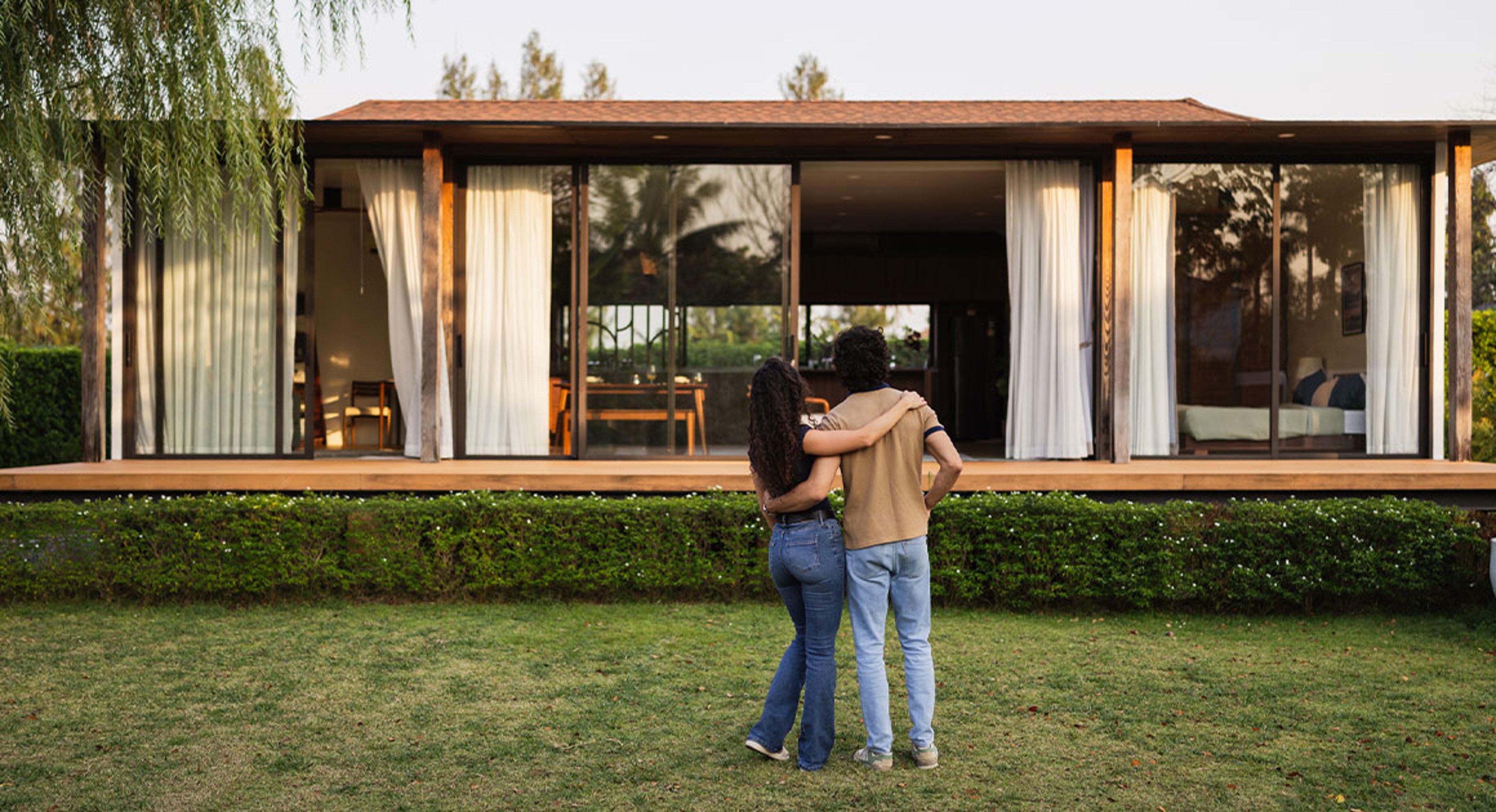 man and woman standing on front lawn looking at house