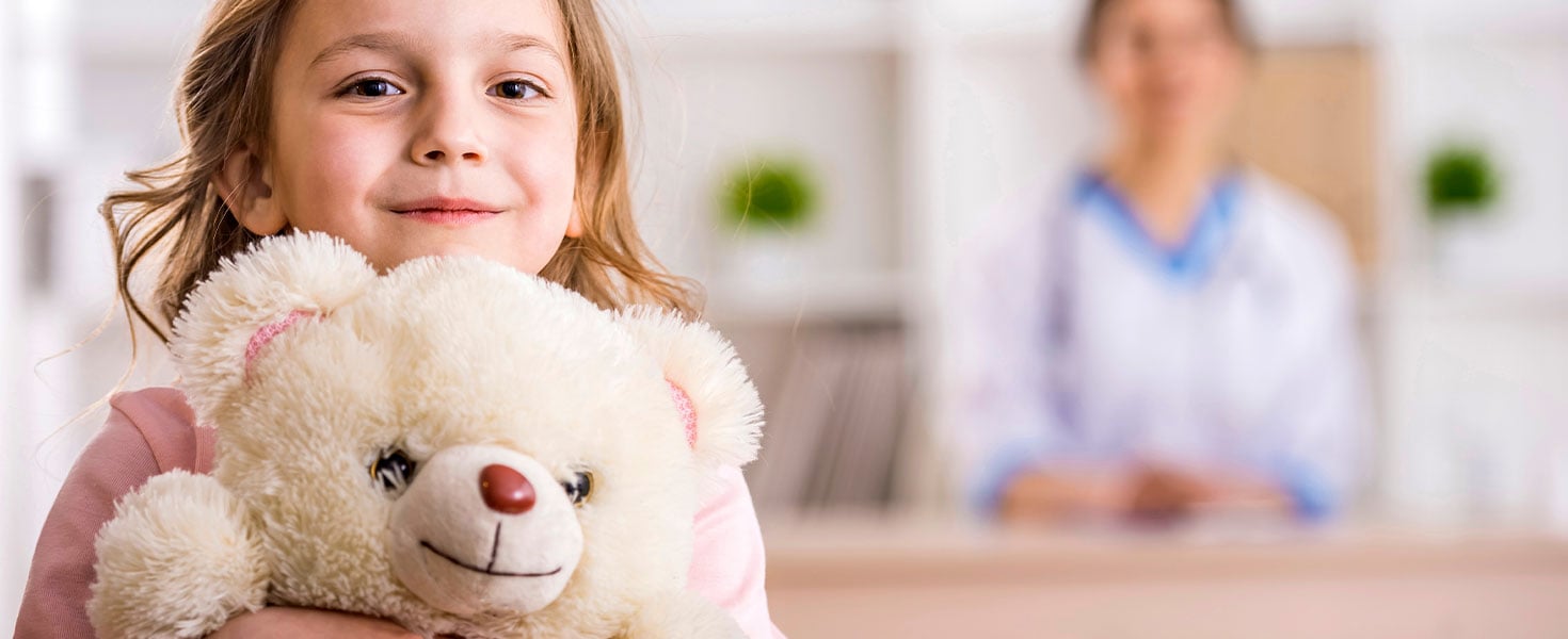 little girl holding bear in hospital waiting room