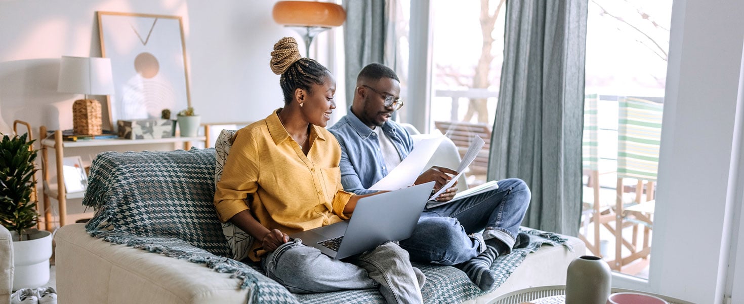 man and woman looking at laptop and documents