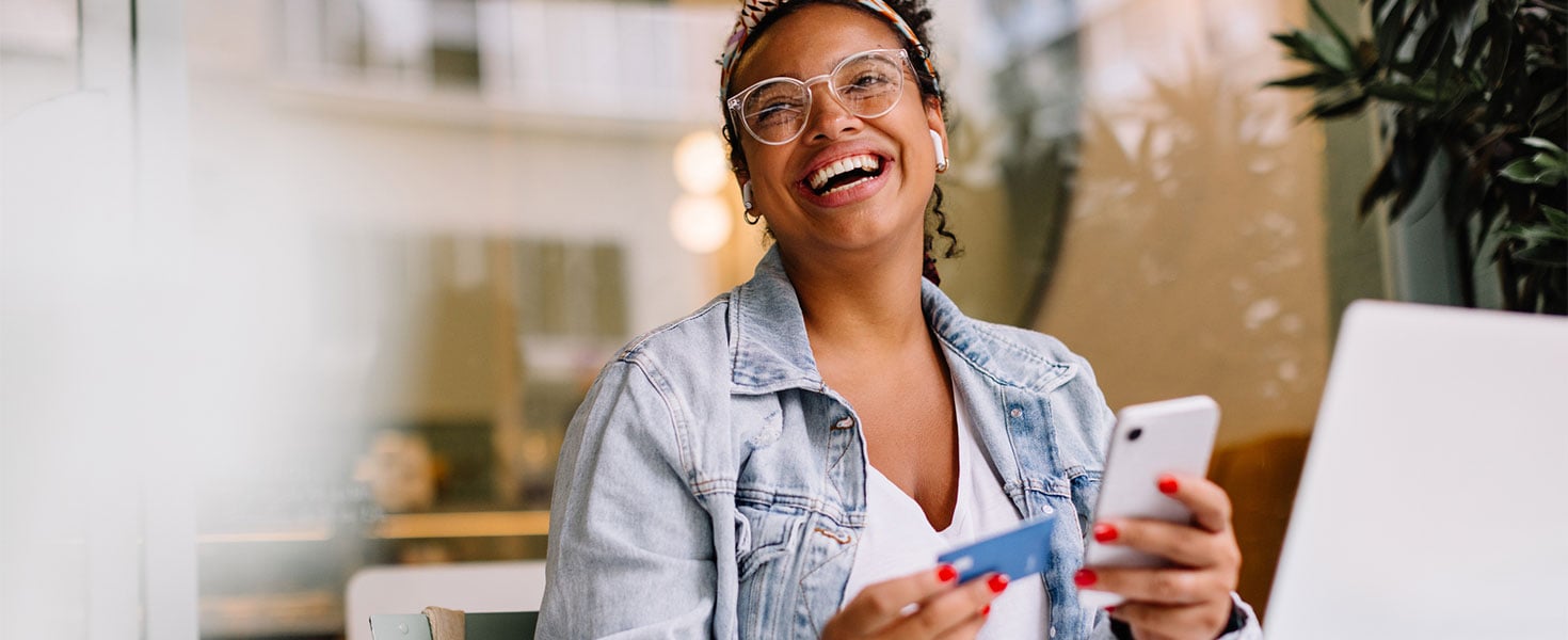 woman smiling holding credit card and phone