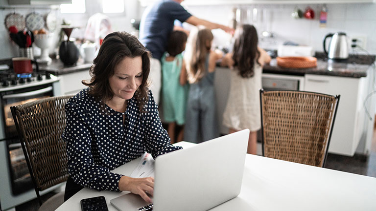 Mature woman working with family in the background at home Credit:FG Trade