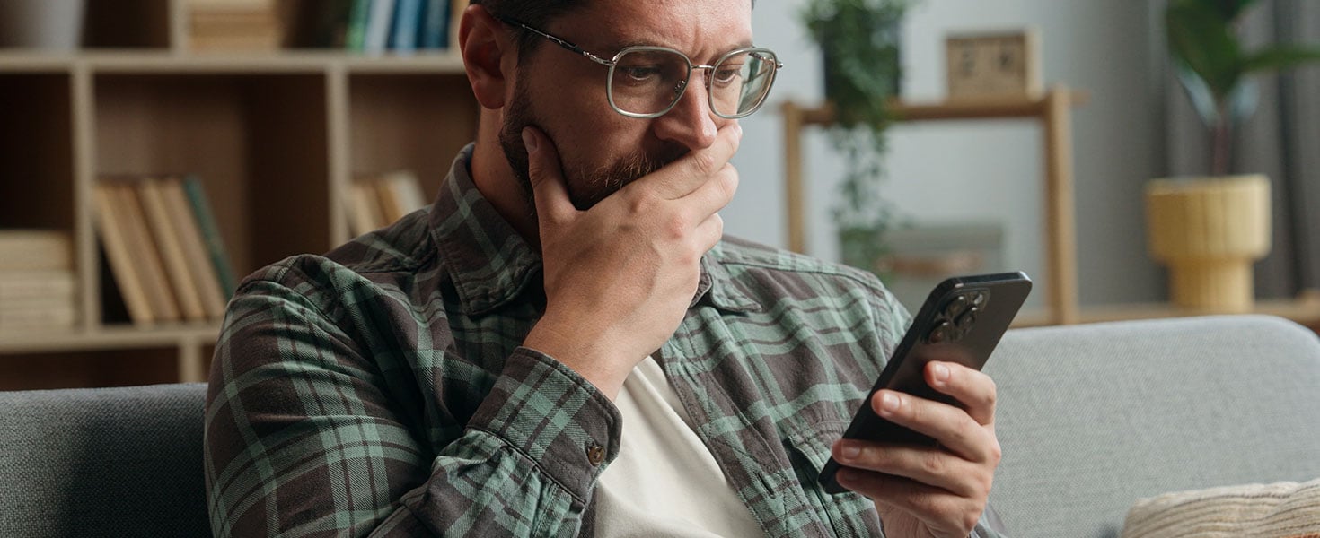 Caucasian adult man male guy at home living room nervous looking at mobile phone bad news amazed shocked close mouth with hand message from bank stressed smartphone notification online error scam See Less by Yuliia