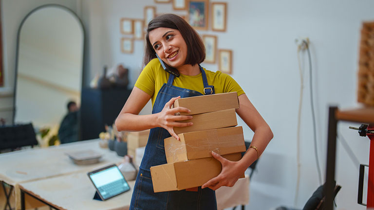 Young woman preparing shipping boxes is talking on the phone. stock photo Credit:ZeynepKaya