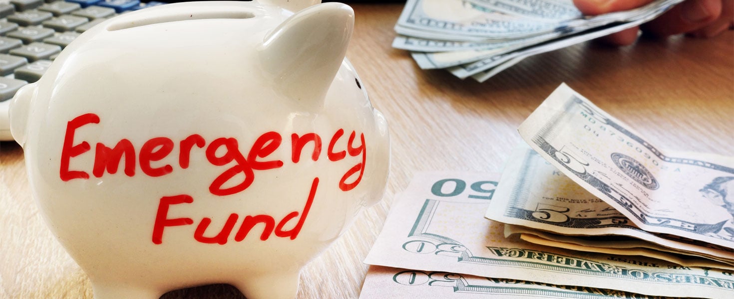 piggy bank labeled emergency fund next to cash