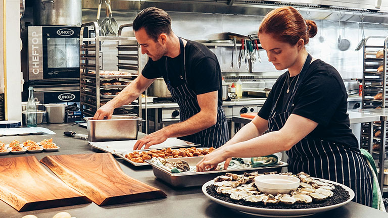 Man and Woman Wearing Black and White Striped Aprons Cooking; Credit: Elle Hughes with Pexels
