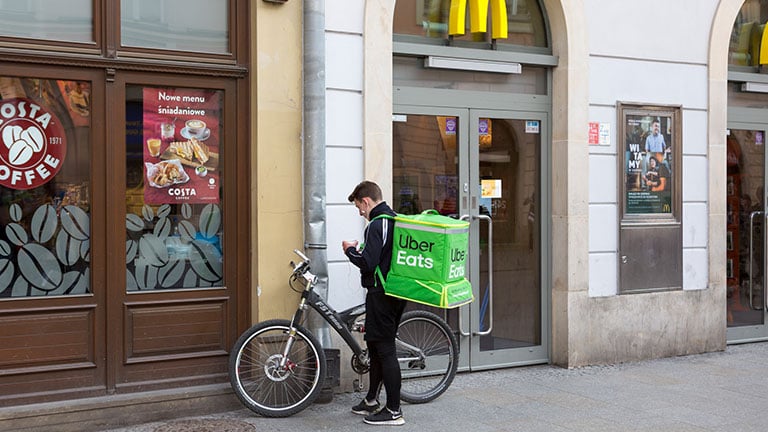 Krakow, Poland Bike Delivery Man in front of a McDonald’s Restaurant, picking up a delivery order. Credit: carterdayne
