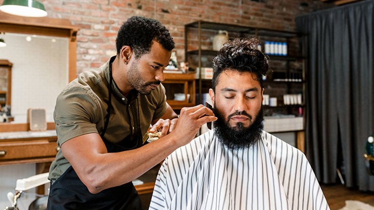 Hairdresser trimming beard of the customer at a barbershop, small business Credit:Rawpixel