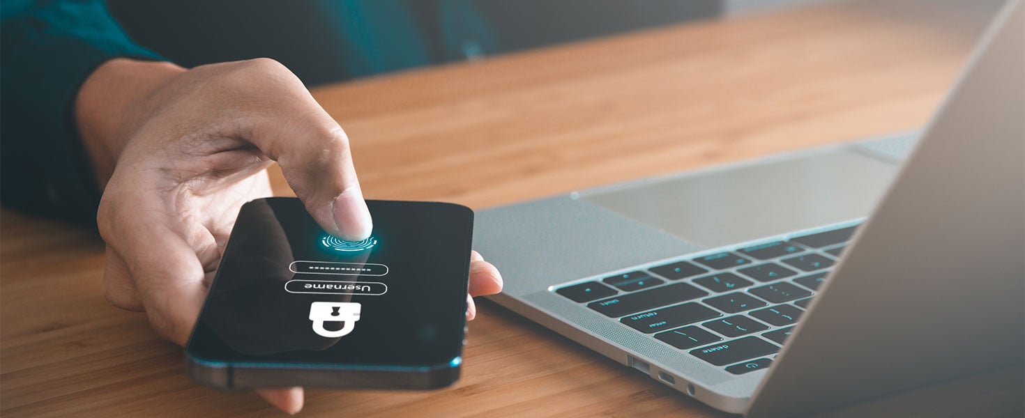 Person using phone to sign into app while on laptop