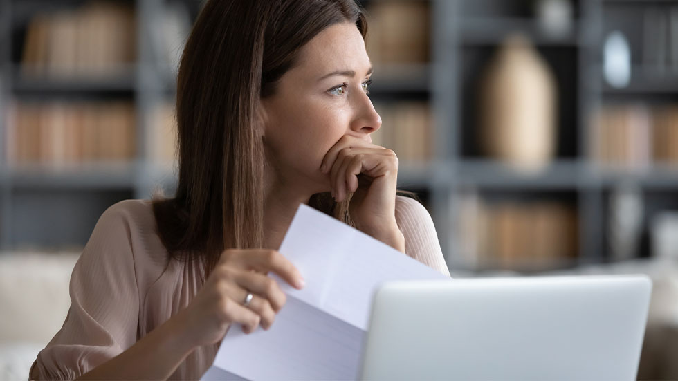 Woman holding document in front of computer