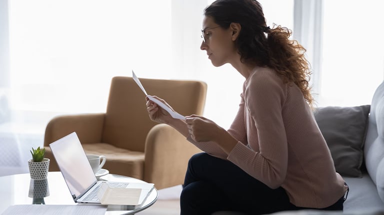woman reading letter near laptop