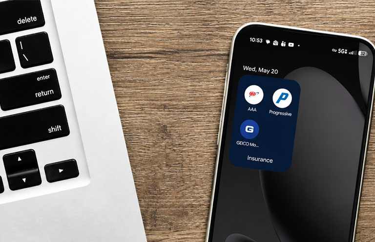 insurance apps on phone next to laptop