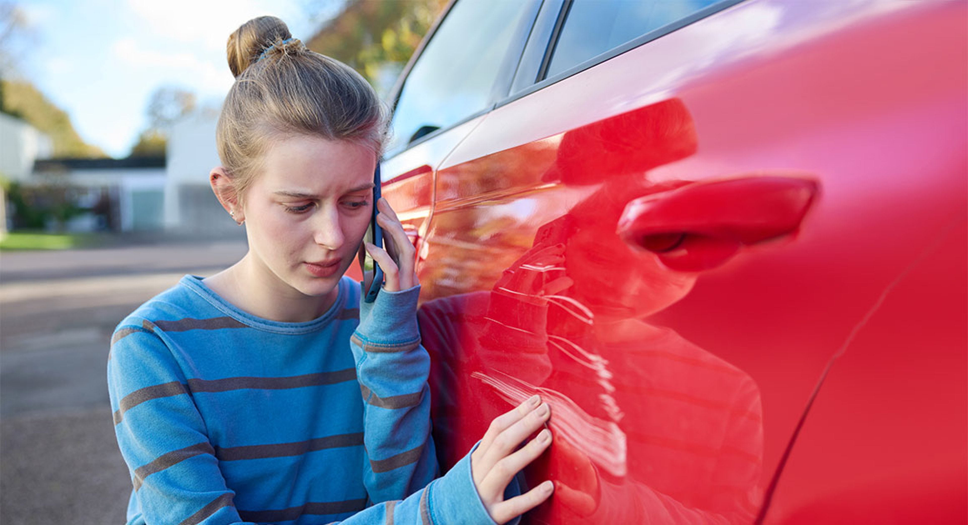 teenager looking at scratch on car door