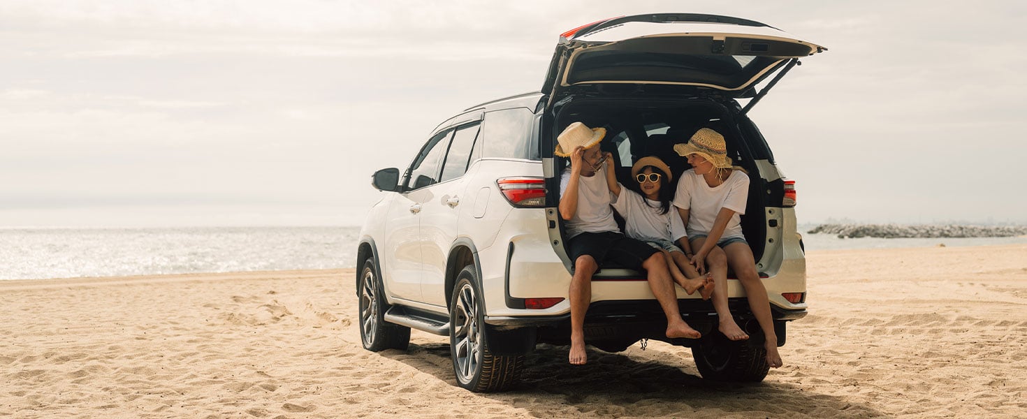 family sitting in car on the beach