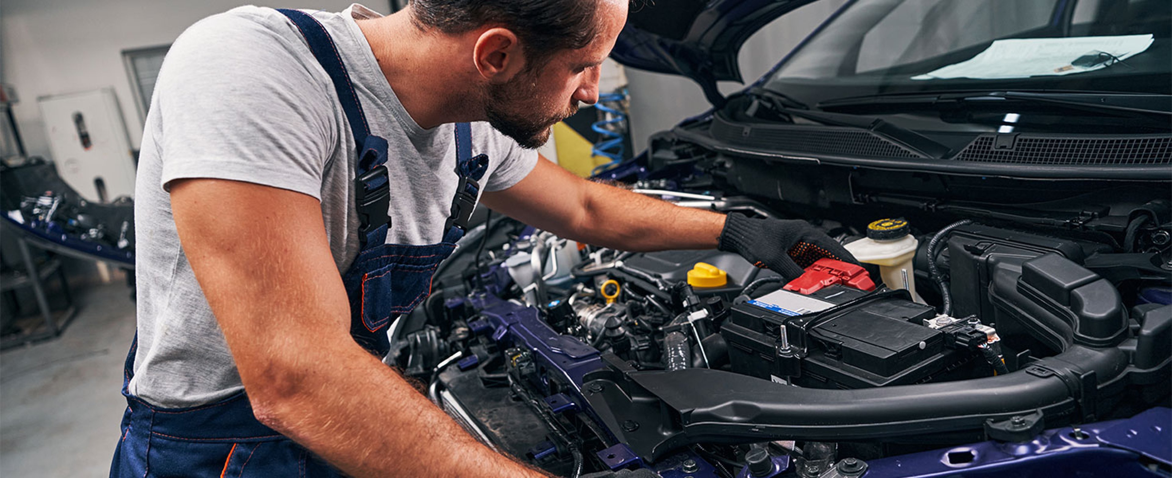 Mechanic looking at battery under car hood