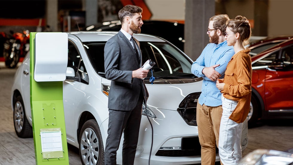 Couple looking at electric car in dealership