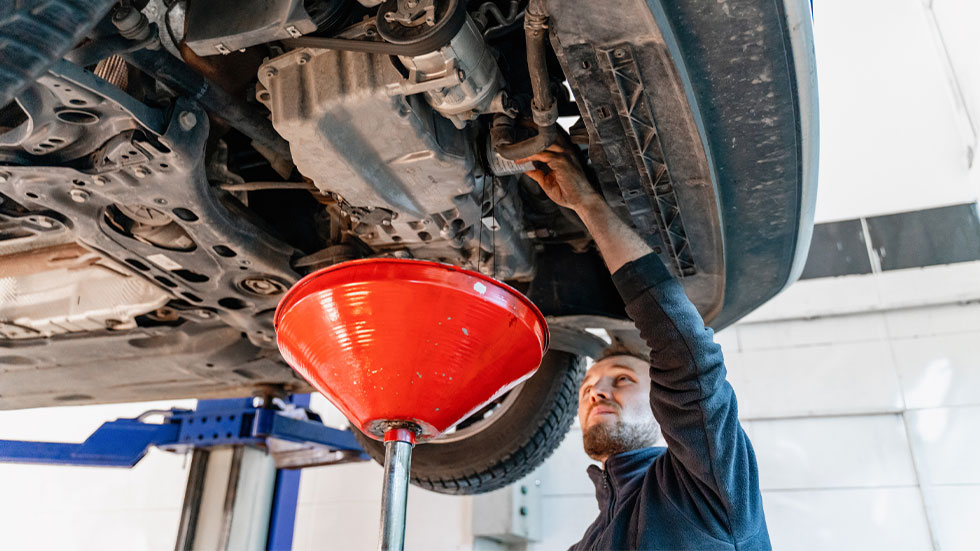 mechanic draining car oil tank