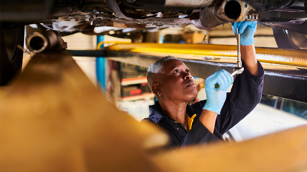 A mechanic diagnostic a problem with auto on laptop at workshop