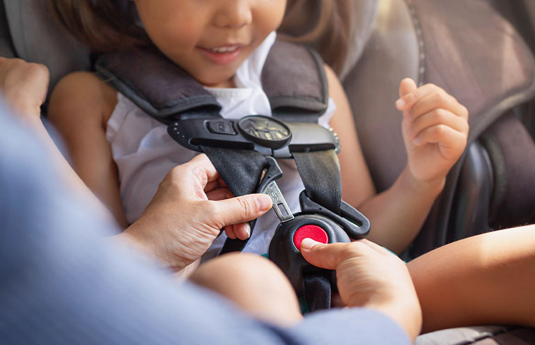 person buckling child into car seat
