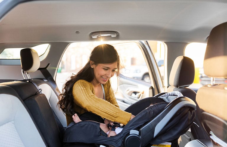 mom putting baby in rear facing car seat