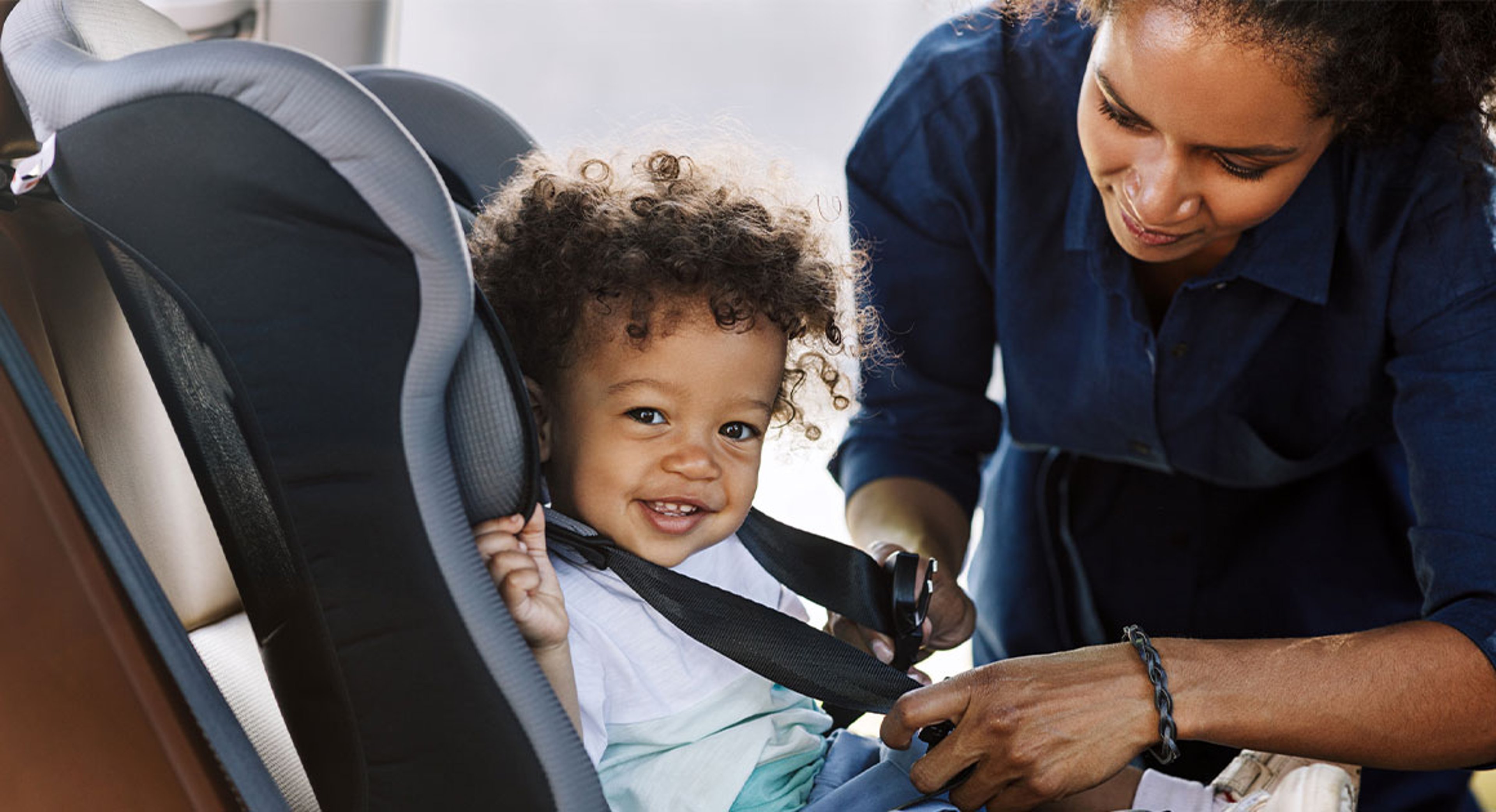 mom buckling baby in car seat