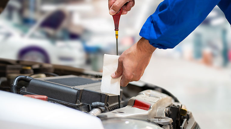 Car mechanic checking oil level in a mechanical at workshop