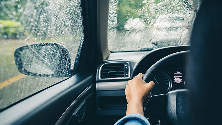 river's hands on steering wheel driving on rainy day; Credit: onsuda