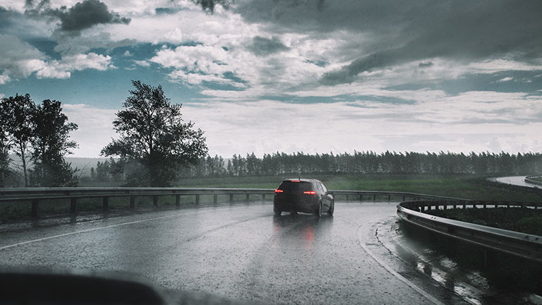 Drive car in rain on curve asphalt wet road; Credit: kurmyshov