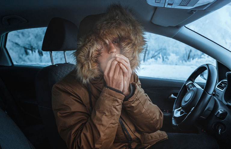 man warming up hands in car, snow outside