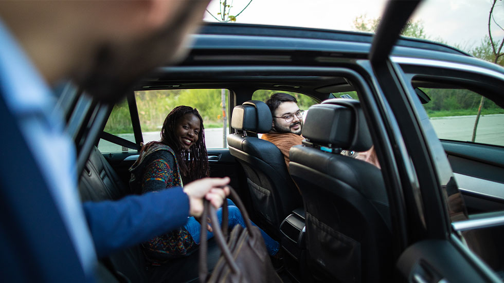 man getting in car with other passengers