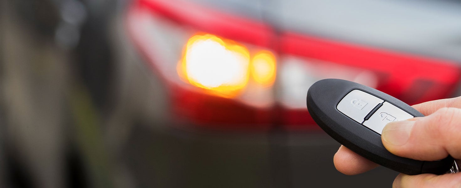 Close up of person locking car with key fob, car in background