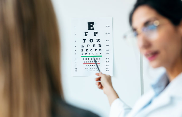 Female optician doing eye test with eye chart on her patient in ophthalmology clinic